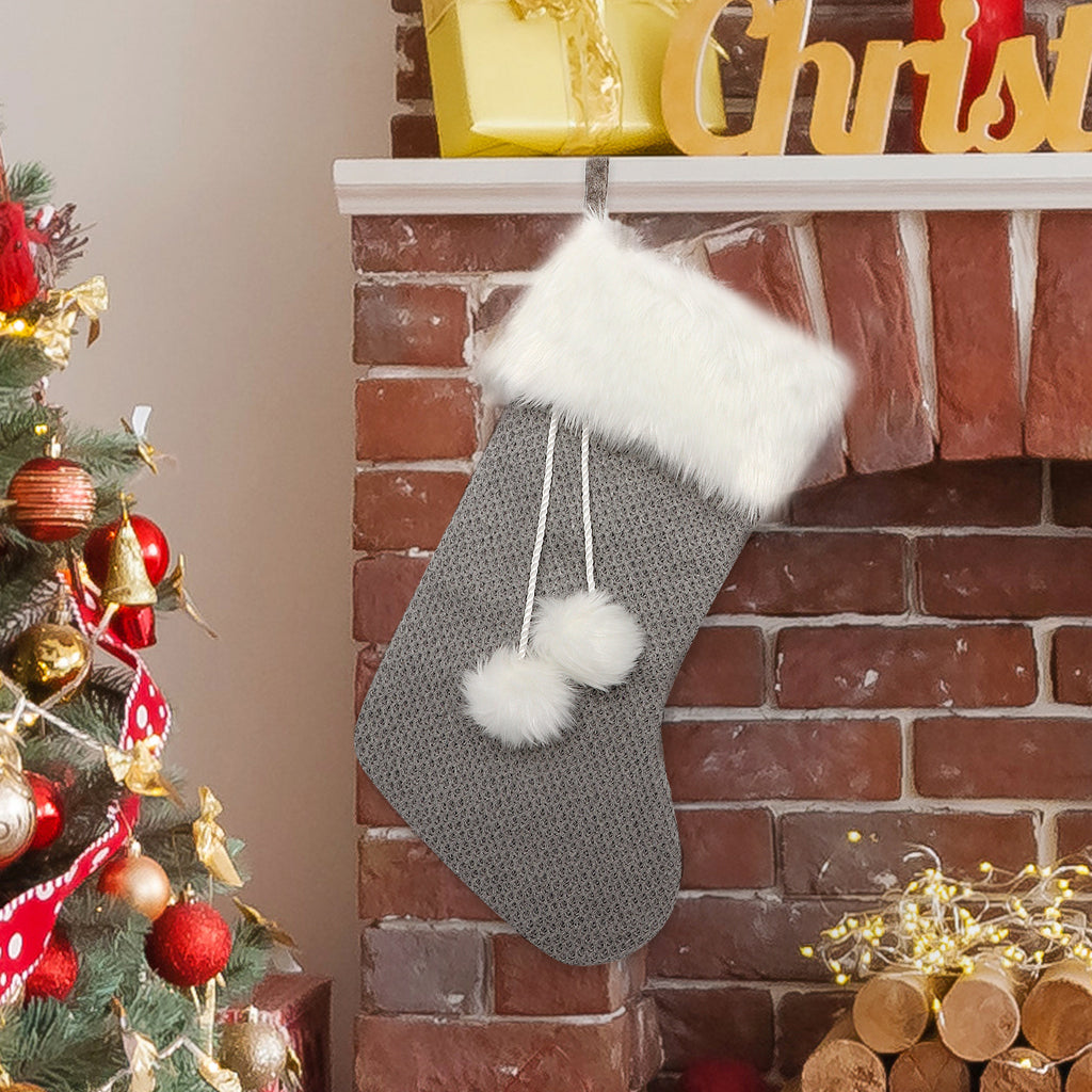 Gray and white knitted Christmas stocking with a pompom at the cuff