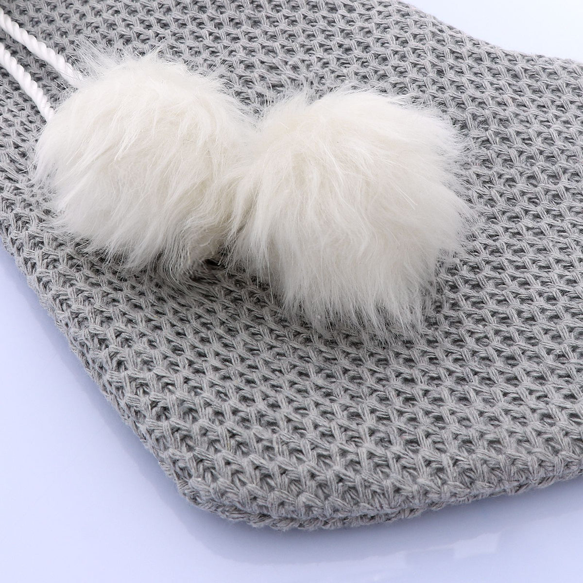 Pompom trim finishing the cuff of the gray and white Christmas stocking